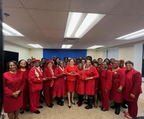 Group photo of persons in a room wearing red dresses